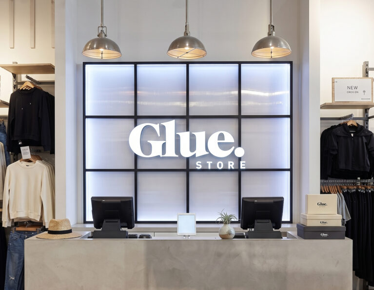 A concrete-rendered point of sale desk set against an illuminated grid wall panel.