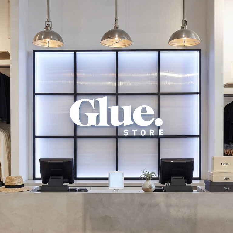 A concrete-rendered point of sale desk set against an illuminated grid wall panel.
