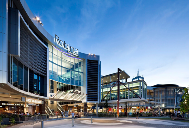A sweeping curved glass facade framing a multi-level entrance plaza and escalators.