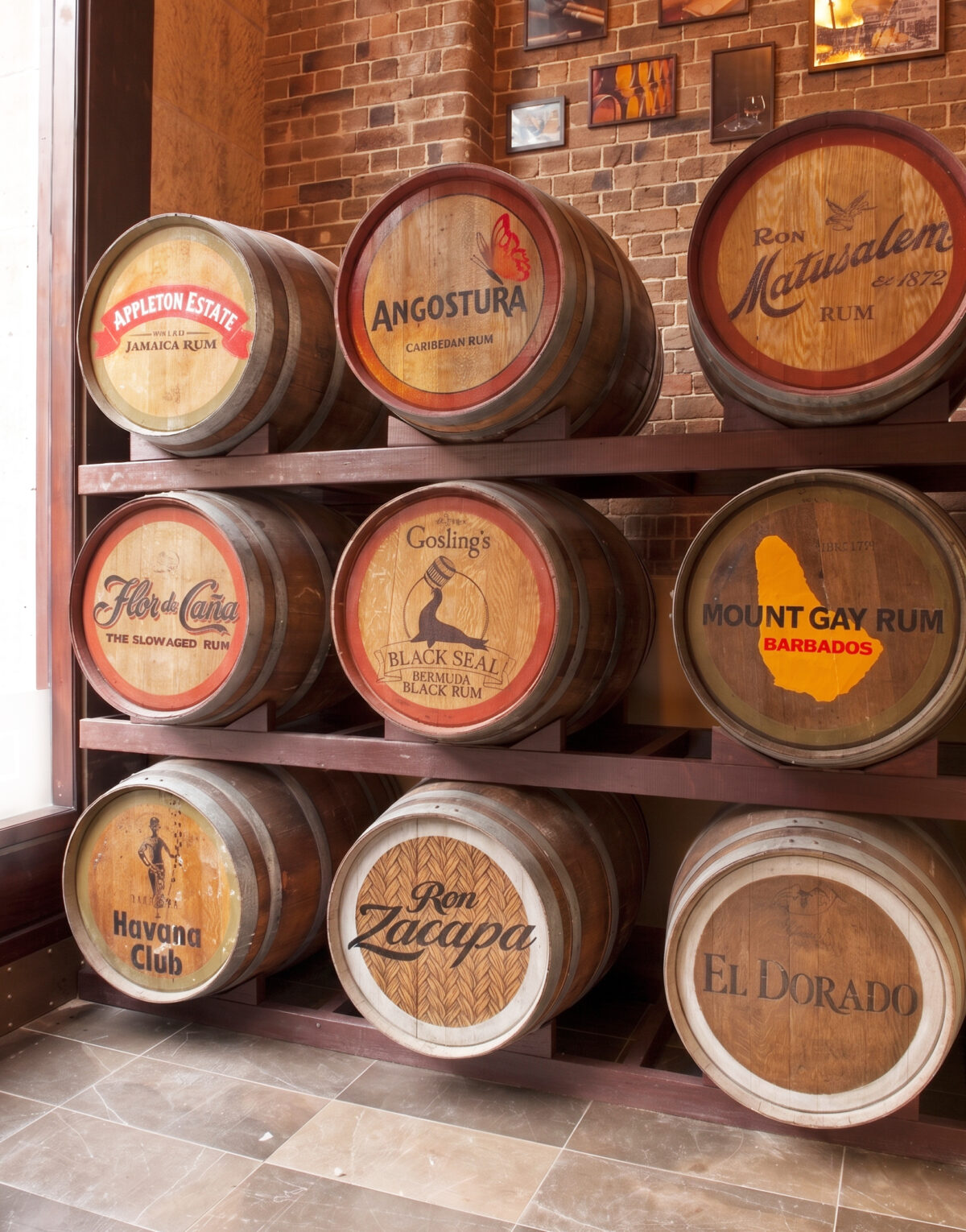 Oak rum barrels, custom cellar racking, branded barrel heads, exposed heritage brick, stone floor tiles, commercial hospitality joinery, vintage product display, thematic restaurant interior.