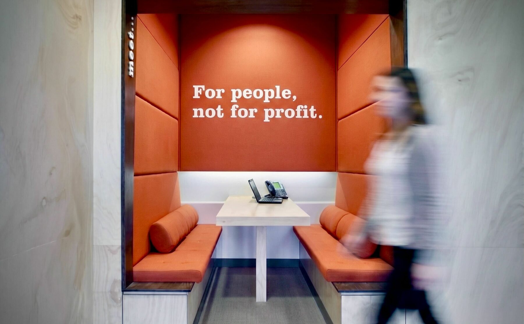 Built in booth seating, acoustic wall panels, plywood wall cladding, terracotta upholstery, integrated meeting portal, corporate ethos typography, commercial banking interior design.