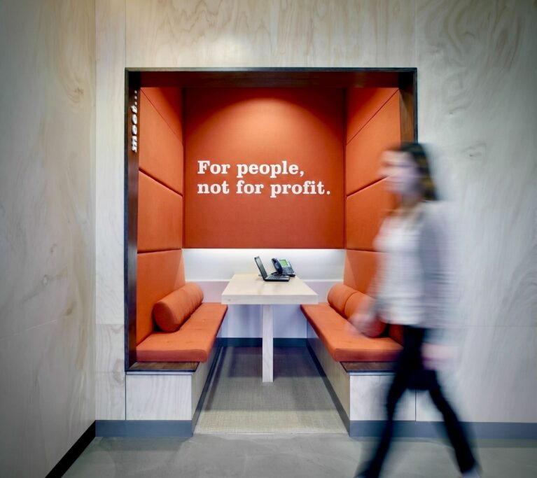 Built in booth seating, acoustic wall panels, plywood wall cladding, terracotta upholstery, integrated meeting portal, corporate ethos typography, commercial banking interior design.