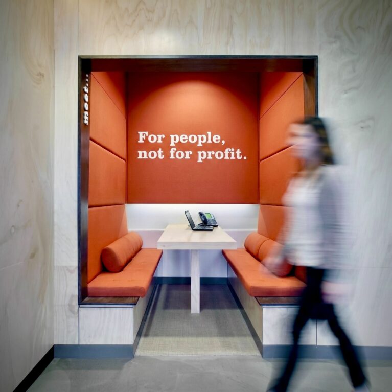 Built in booth seating, acoustic wall panels, plywood wall cladding, terracotta upholstery, integrated meeting portal, corporate ethos typography, commercial banking interior design.