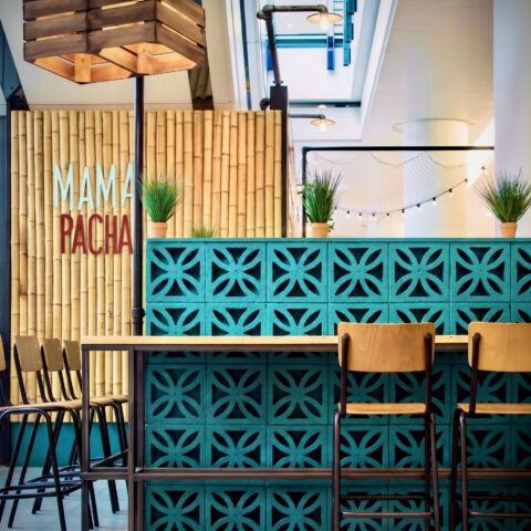 Breeze block screen wall, turquoise concrete blocks, bamboo wall cladding, custom timber pendant, industrial bar stools, commercial cafe zoning, architectural screening, high topped dining table.