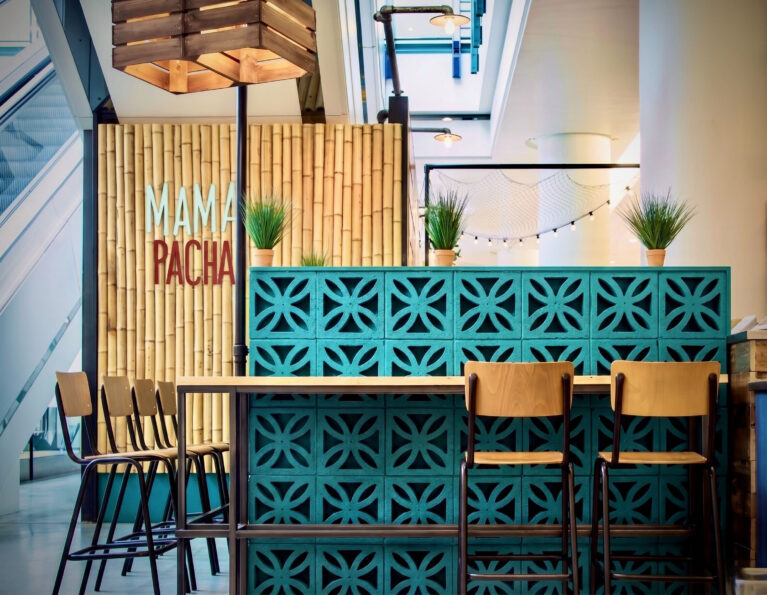 Breeze block screen wall, turquoise concrete blocks, bamboo wall cladding, custom timber pendant, industrial bar stools, commercial cafe zoning, architectural screening, high topped dining table.