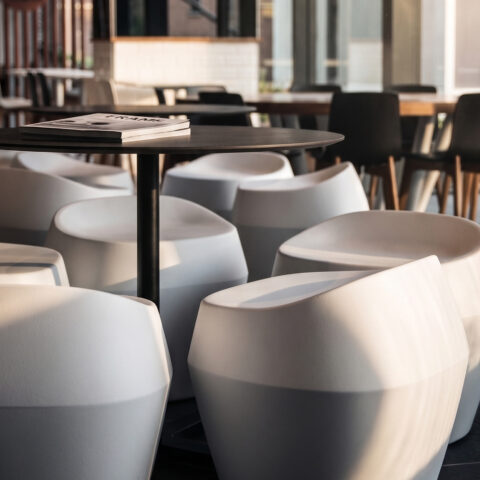 Commercial food court, molded composite stools, circular café tables, timber dining chairs, angular spatial layout, commercial floor tiles, community hub seating.