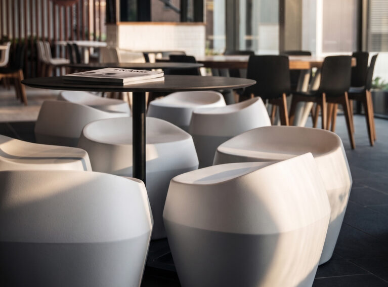 Commercial food court, molded composite stools, circular café tables, timber dining chairs, angular spatial layout, commercial floor tiles, community hub seating.