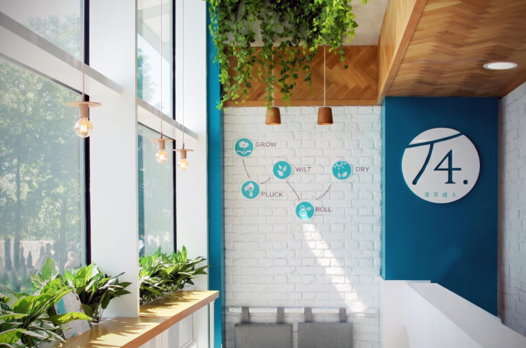 Retail store interior, white brick feature wall, window service counter, hanging ivy planter, industrial bulb pendant lights, circular brand signage.