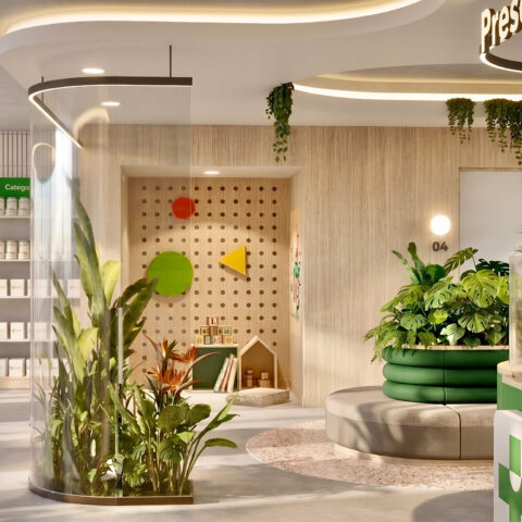 A calm waiting area with curved seating, lush planting, and a children’s play corner, positioned adjacent to the prescription counter to create a welcoming, family-oriented environment.