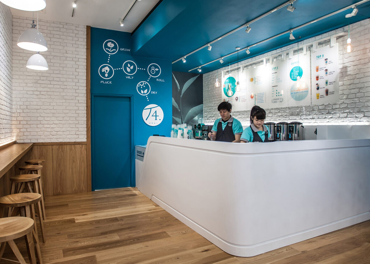 Bubble tea service counter, curved solid surface joinery, teal bulkhead paint, white brick veneer wall, architectural track lighting, timber bar stools, commercial beverage station, retail kiosk layout.
