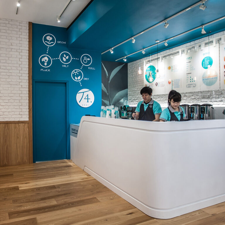 Bubble tea service counter, curved solid surface joinery, teal bulkhead paint, white brick veneer wall, architectural track lighting, timber bar stools, commercial beverage station, retail kiosk layout.