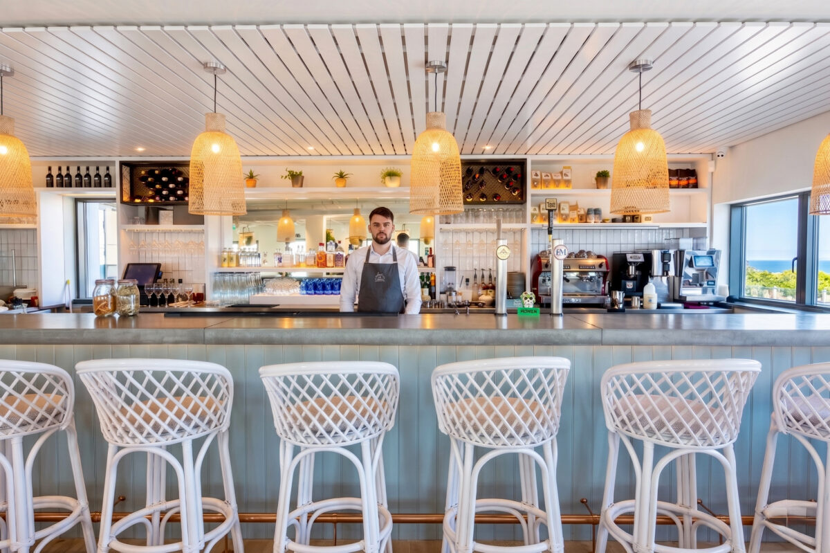 Linear bar counter featuring woven wicker pendants and woven-backed stools.