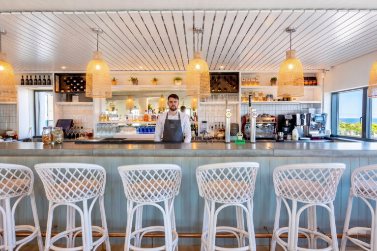 Linear bar counter featuring woven wicker pendants and woven-backed stools.