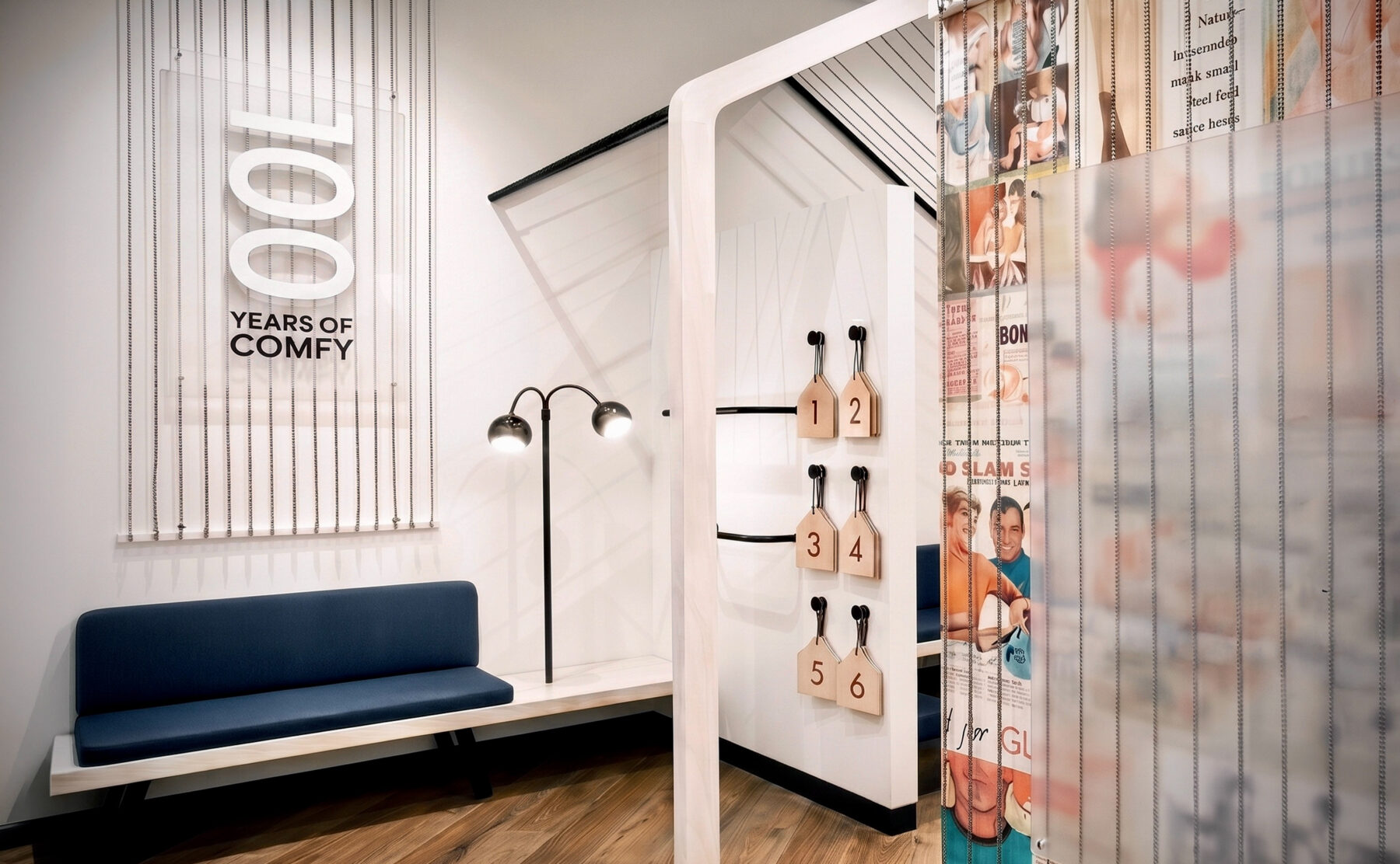Retail changing rooms, timber flooring, upholstered bench seating, dimensional wall signage, heritage graphic curtains, minimalist floor lamps, commercial fit-out.