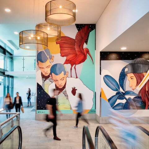 Commercial entrance, wall mural, pendant lights, vertical green wall, escalator, pedestrian traffic, terrazzo flooring, geometric panels.