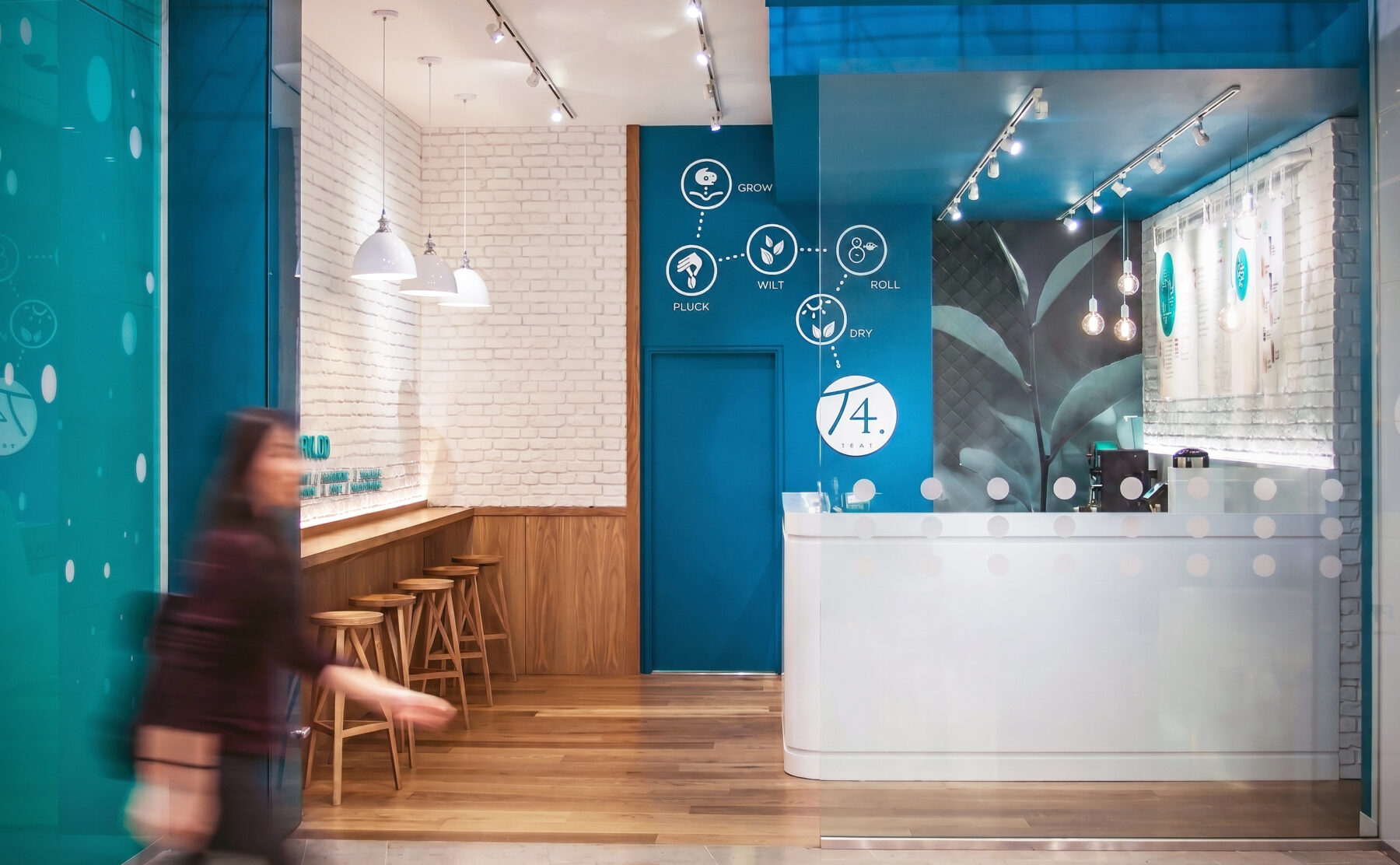 Shopping mall storefront, commercial tea shop facade, teal architectural bulkhead, glass retail partition, recessed ceiling downlights, wire frame installation, timber bar seating, open entrance layout.