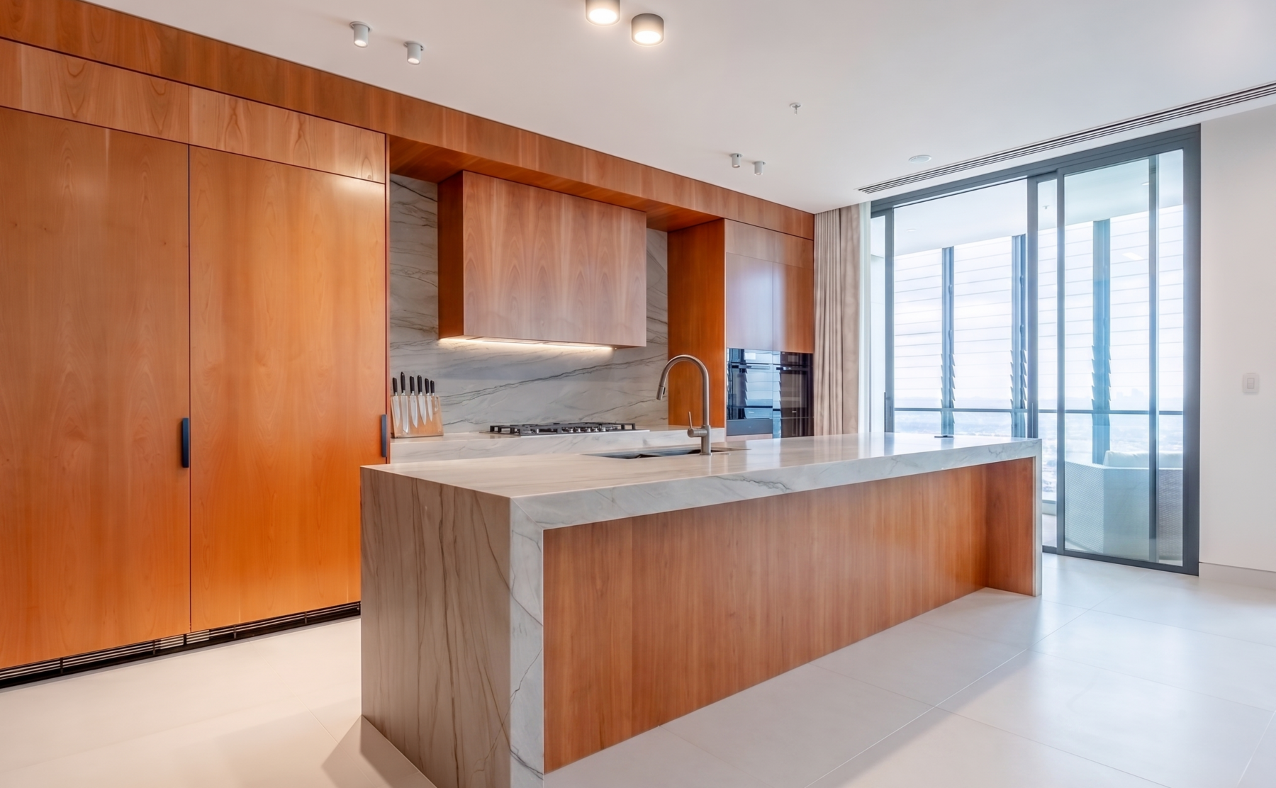 The generous kitchen island features an expansive Quartzite countertop and comfortable leather upholstered bar stools, creating a perfect space for dining and gatherings. Added extras include a pop-up GPO tower for family device charging.