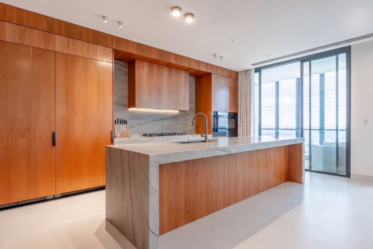 The generous kitchen island features an expansive Quartzite countertop and comfortable leather upholstered bar stools, creating a perfect space for dining and gatherings. Added extras include a pop-up GPO tower for family device charging.