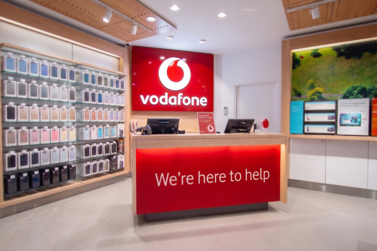 Another view of the Vodafone welcome desk, featuring vibrant signage and neatly arranged product displays.