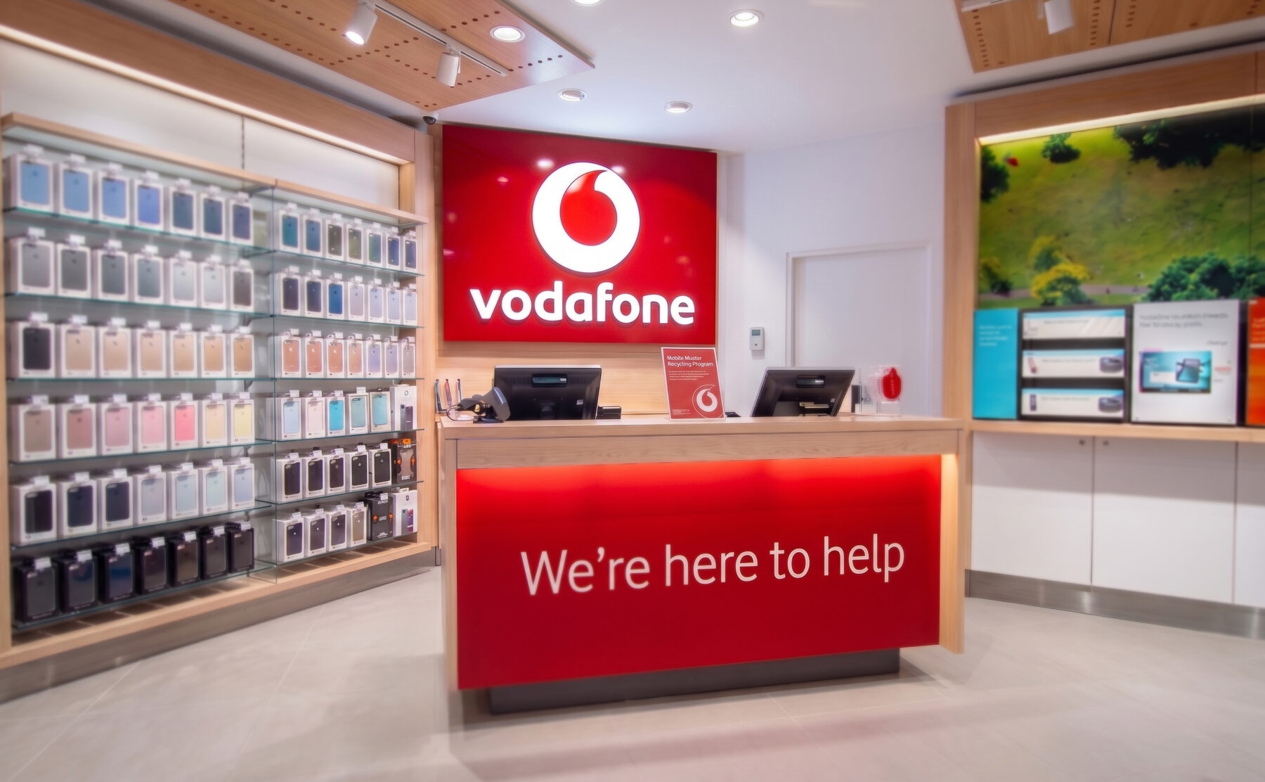 Another view of the Vodafone welcome desk, featuring vibrant signage and neatly arranged product displays.