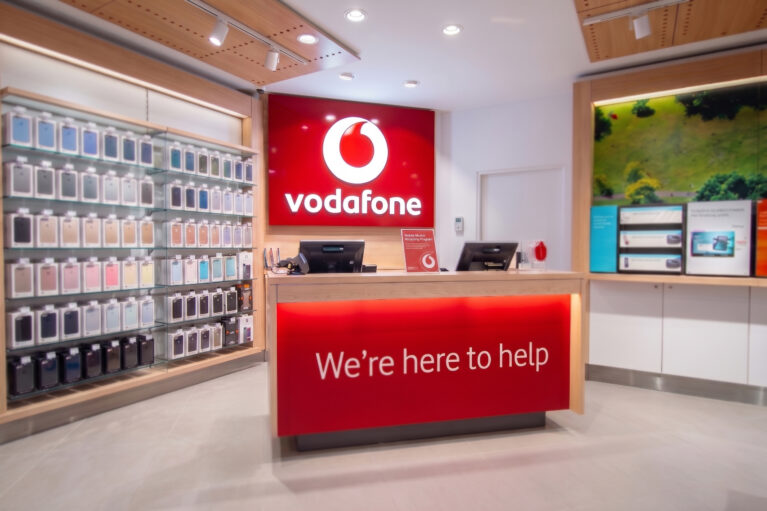 Another view of the Vodafone welcome desk, featuring vibrant signage and neatly arranged product displays.