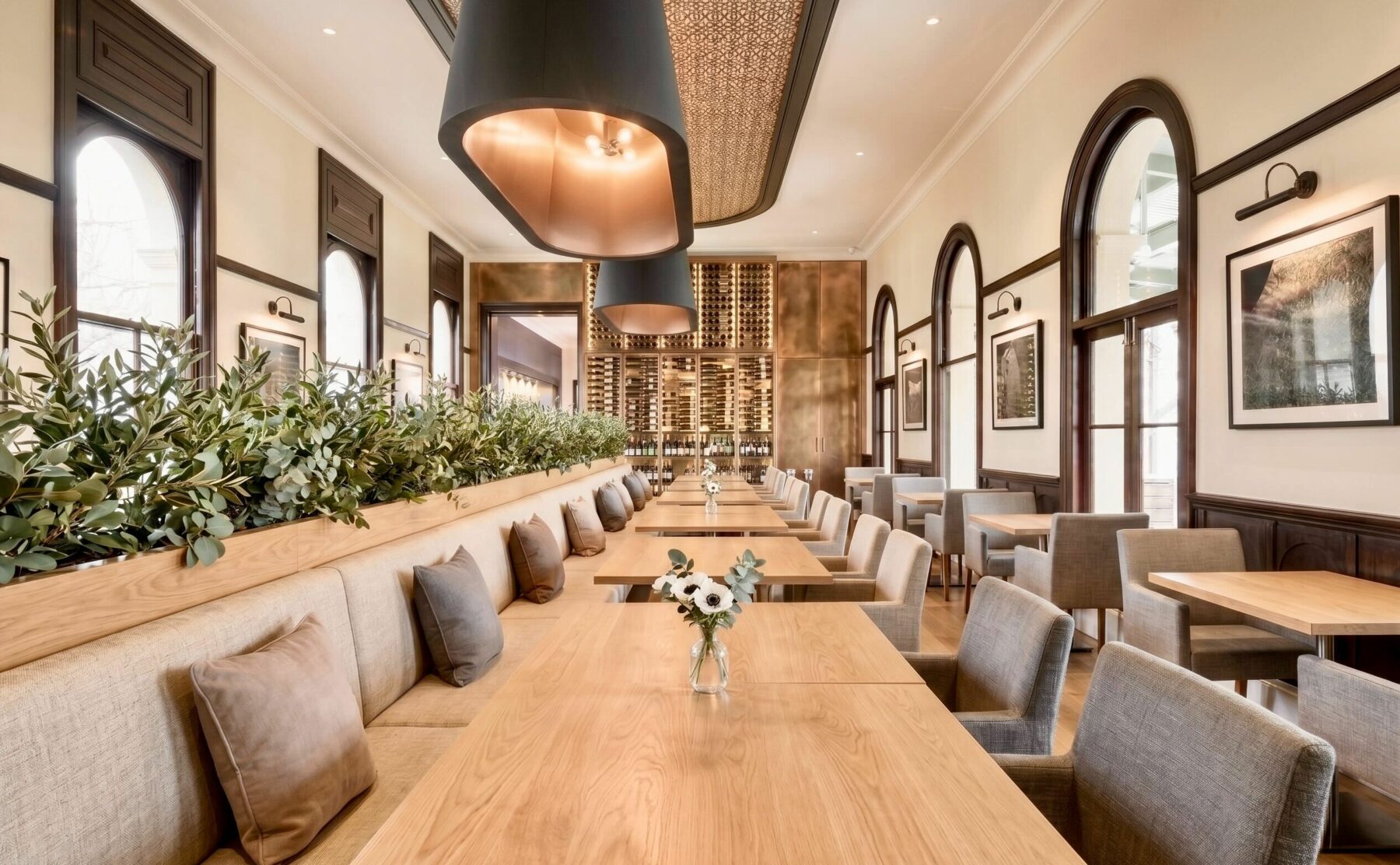 Heritage restaurant dining room, custom banquette seating, timber dining tables, arched window frames, oversized pendant lights, gold lining, parquetry ceiling feature, planters.