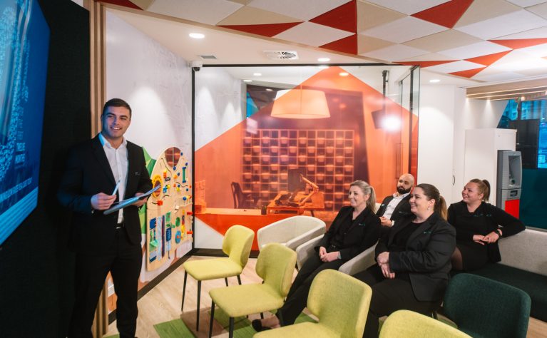 Heritage Bank’s flexible meeting area, designed for presentations and seminars, with a modern, casual setup featuring an interactive screen and colorful seating.