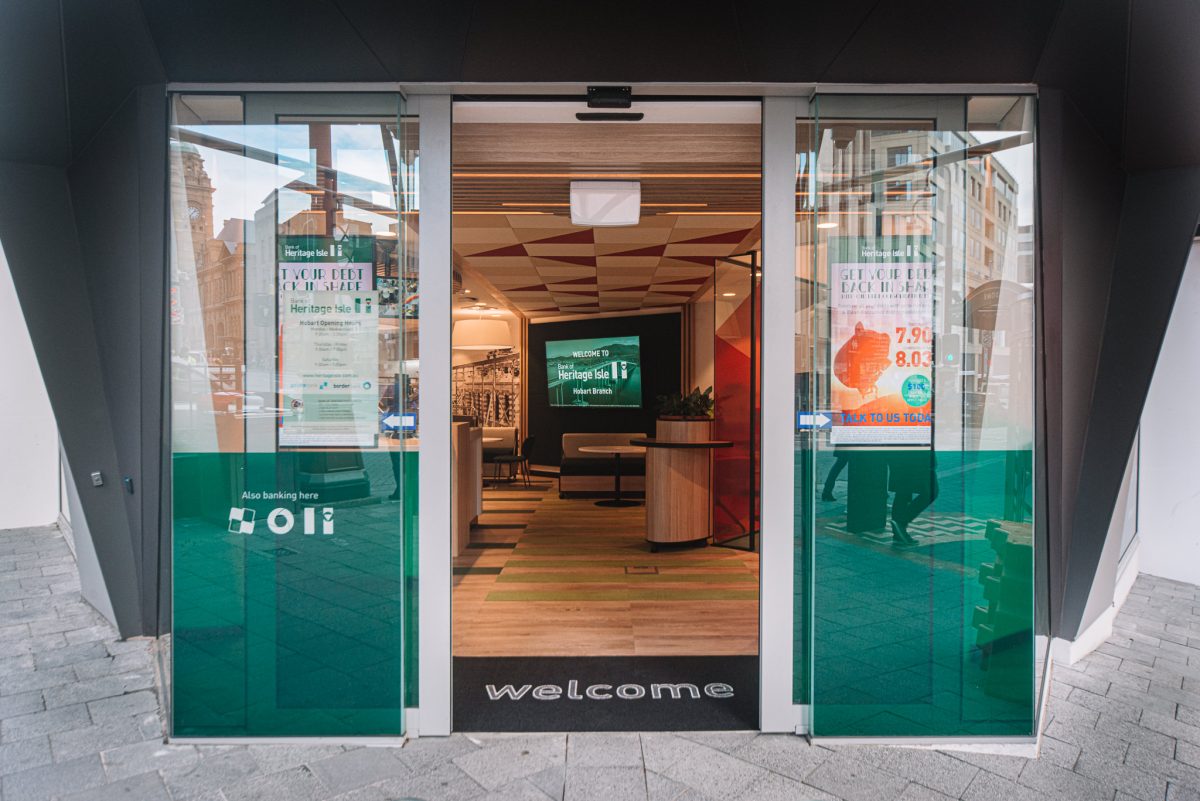 The inviting glass entrance of the branch, featuring tinted forest green doors, minimalist interiors, and a welcoming, modern aesthetic.