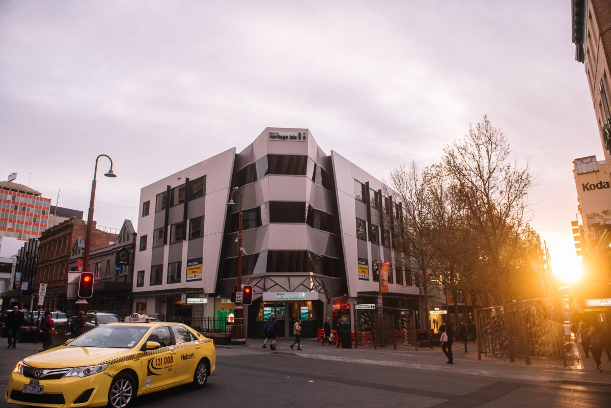 Heritage Bank's striking angular facade is illuminated by the golden hues of sunset, enhancing its modern design and prominent presence in the cityscape.