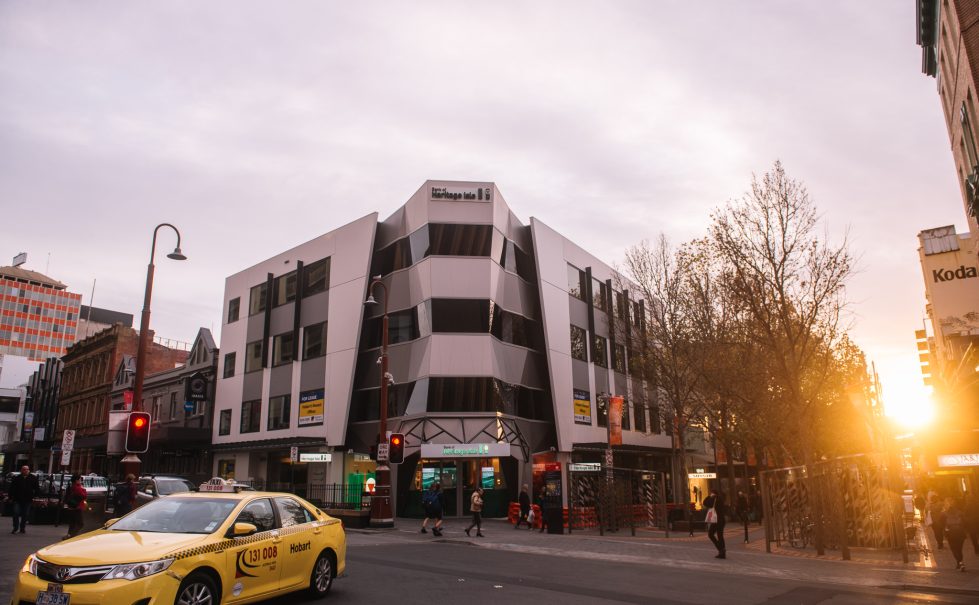 Heritage Bank's striking angular facade is illuminated by the golden hues of sunset, enhancing its modern design and prominent presence in the cityscape.