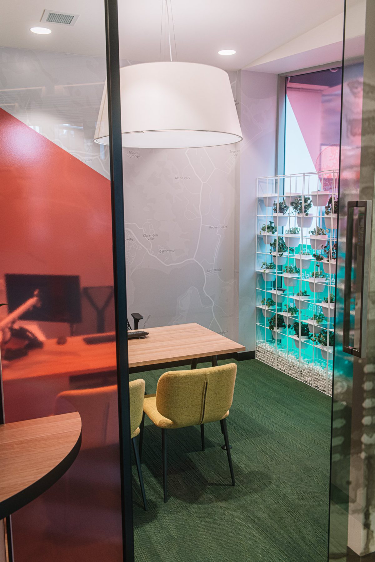 A private, modern meeting room at Heritage Bank with a minimalist design, featuring warm wood accents, vibrant greenery, and a unique topographical wall pattern.