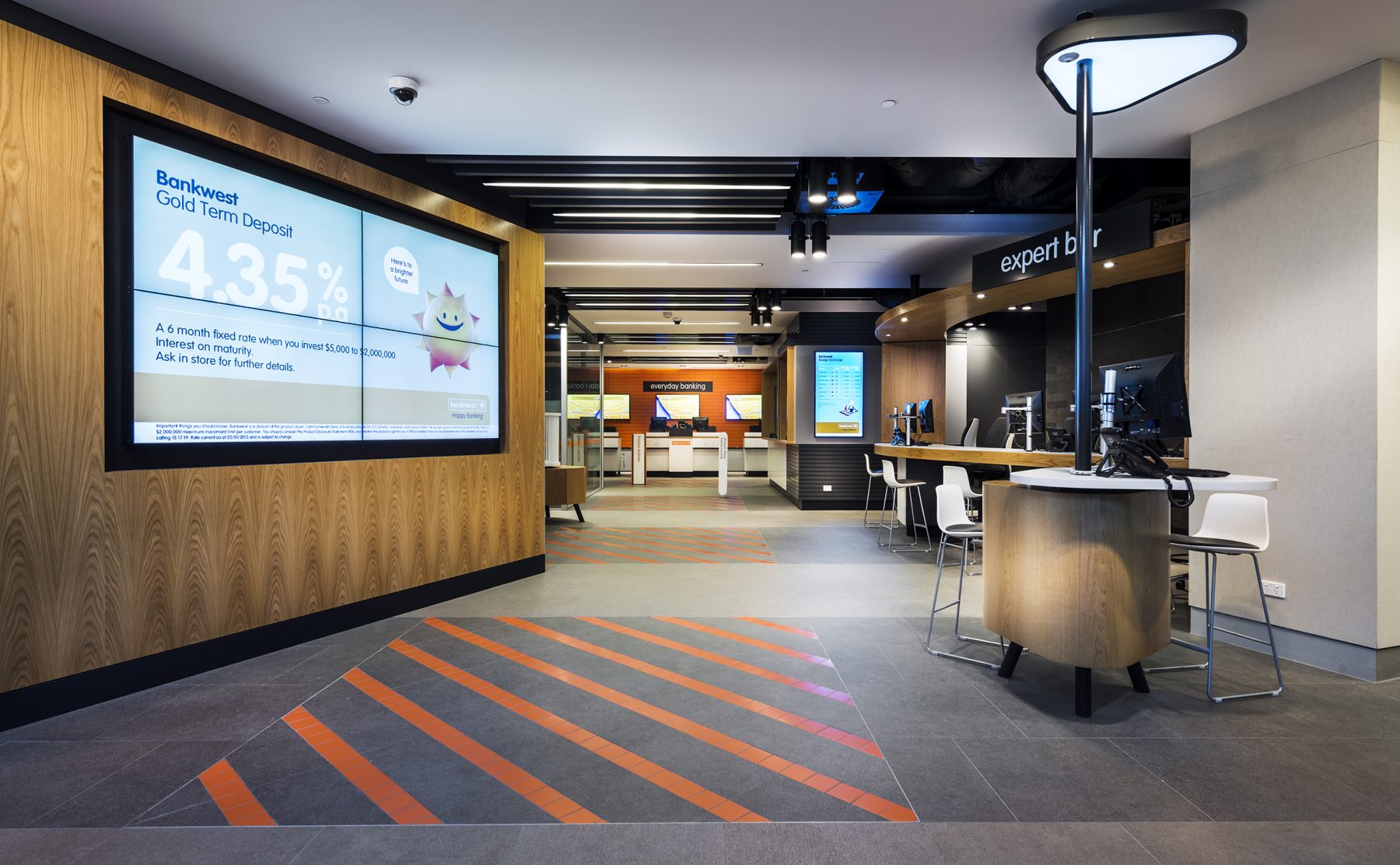 Main entry corridor featuring graphic flooring, digital screens, and open-plan service pods.