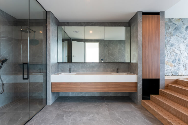 The master ensuite’s double vanity provides ample space and style, with a wood and stone combination, sleek fixtures, and full-length mirrors that enhance the room’s functionality and elegance.