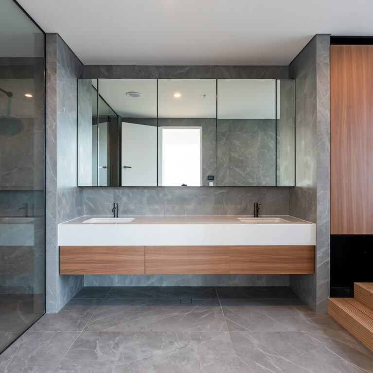 The master ensuite’s double vanity provides ample space and style, with a wood and stone combination, sleek fixtures, and full-length mirrors that enhance the room’s functionality and elegance.