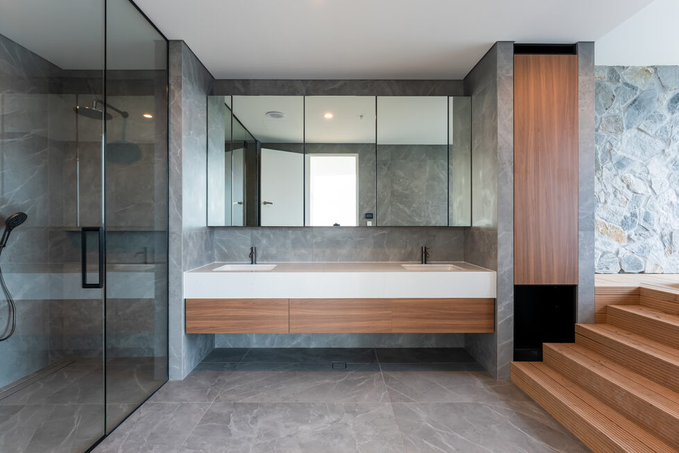 The master ensuite’s double vanity provides ample space and style, with a wood and stone combination, sleek fixtures, and full-length mirrors that enhance the room’s functionality and elegance.