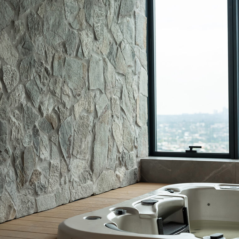 An elevated spa area with a natural stone wall creates a rustic, luxurious ambiance, offering a private retreat for relaxation within the master suite.