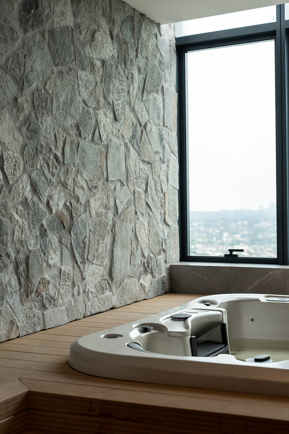 An elevated spa area with a natural stone wall creates a rustic, luxurious ambiance, offering a private retreat for relaxation within the master suite.