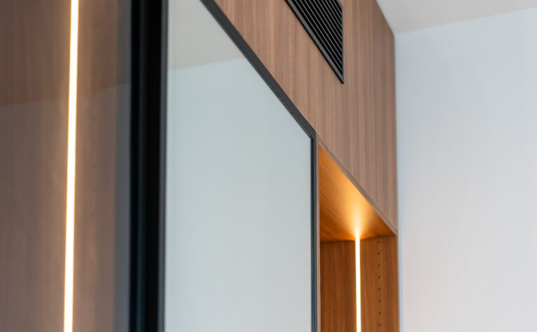 Subtle lighting and warm wood tones in the master suite’s closet highlight the attention to detail, enhancing the elegance of the space and creating a soft, inviting glow.