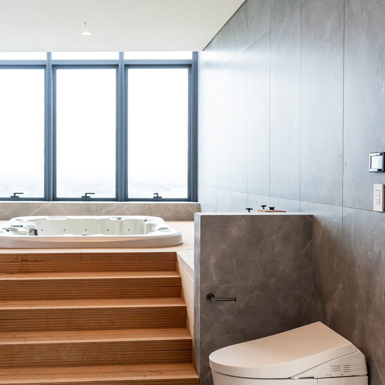 The spa area’s seamless integration of a jacuzzi, wooden steps, and sleek fixtures offers a private, luxurious bathing experience with panoramic views, embodying the apartment’s balance of luxury and practicality.