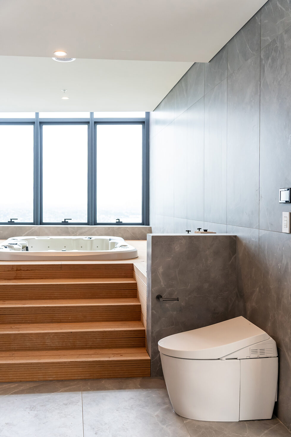 The spa area’s seamless integration of a jacuzzi, wooden steps, and sleek fixtures offers a private, luxurious bathing experience with panoramic views, embodying the apartment’s balance of luxury and practicality.