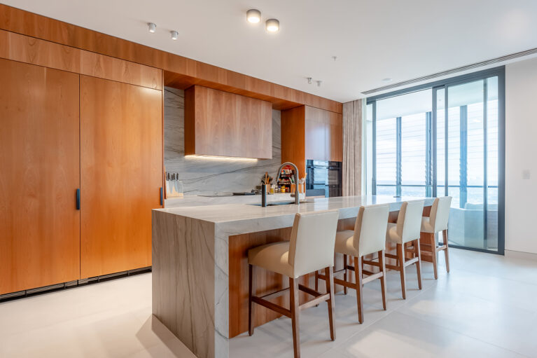 The generous kitchen island features an expansive Quartzite countertop and comfortable leather upholstered bar stools, creating a perfect space for dining and gatherings. Added extras include a pop-up GPO tower for family device charging.