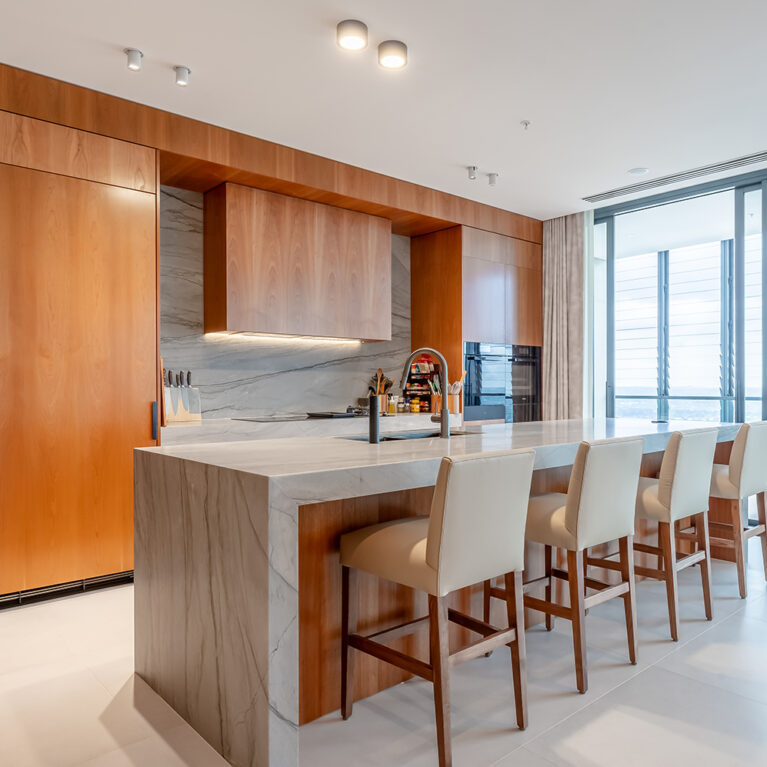 The generous kitchen island features an expansive Quartzite countertop and comfortable leather upholstered bar stools, creating a perfect space for dining and gatherings. Added extras include a pop-up GPO tower for family device charging.