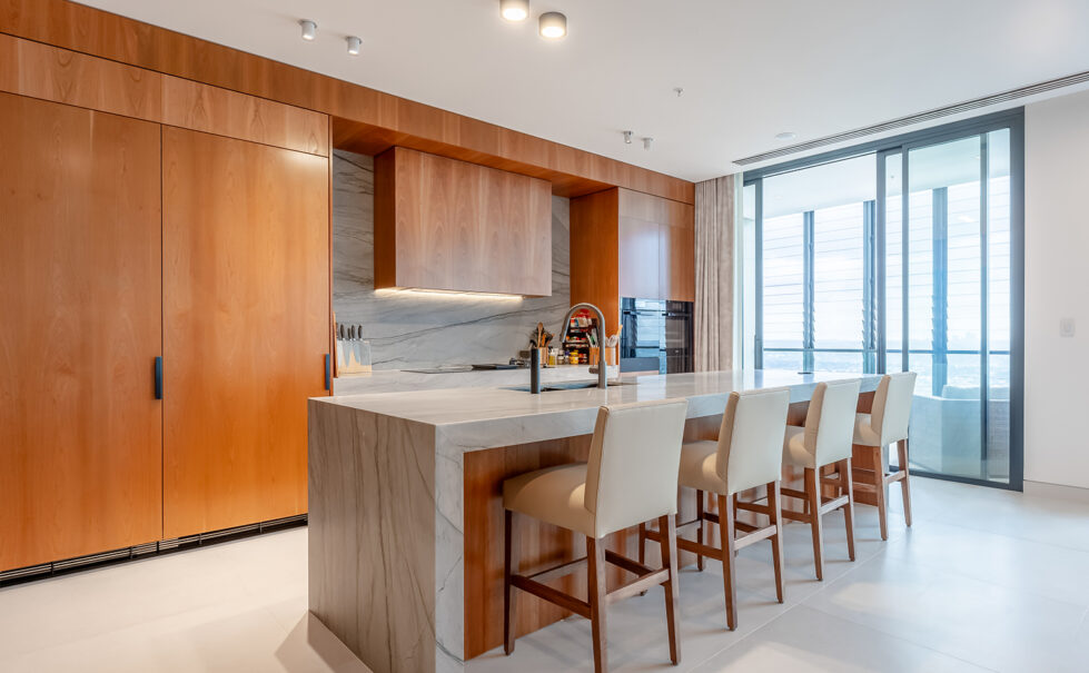 The generous kitchen island features an expansive Quartzite countertop and comfortable leather upholstered bar stools, creating a perfect space for dining and gatherings. Added extras include a pop-up GPO tower for family device charging.