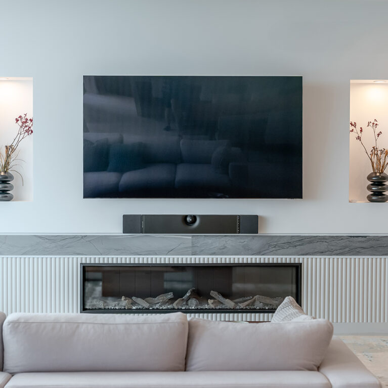 The living room’s entertainment wall combines function and style, with a minimalist design featuring a recessed TV, display niches, and a modern fireplace. 