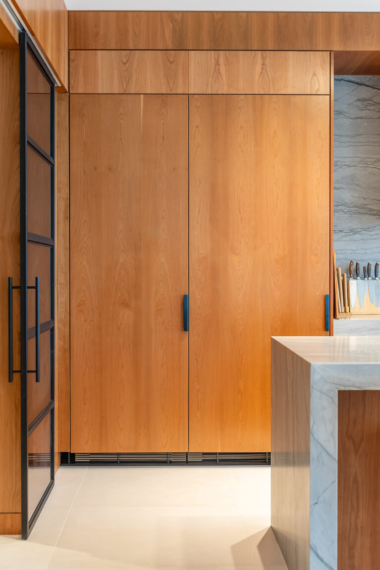 The light-brown wooden cabinets housing an integrated fridge/freezer, showcasing modern design and elegant materials.