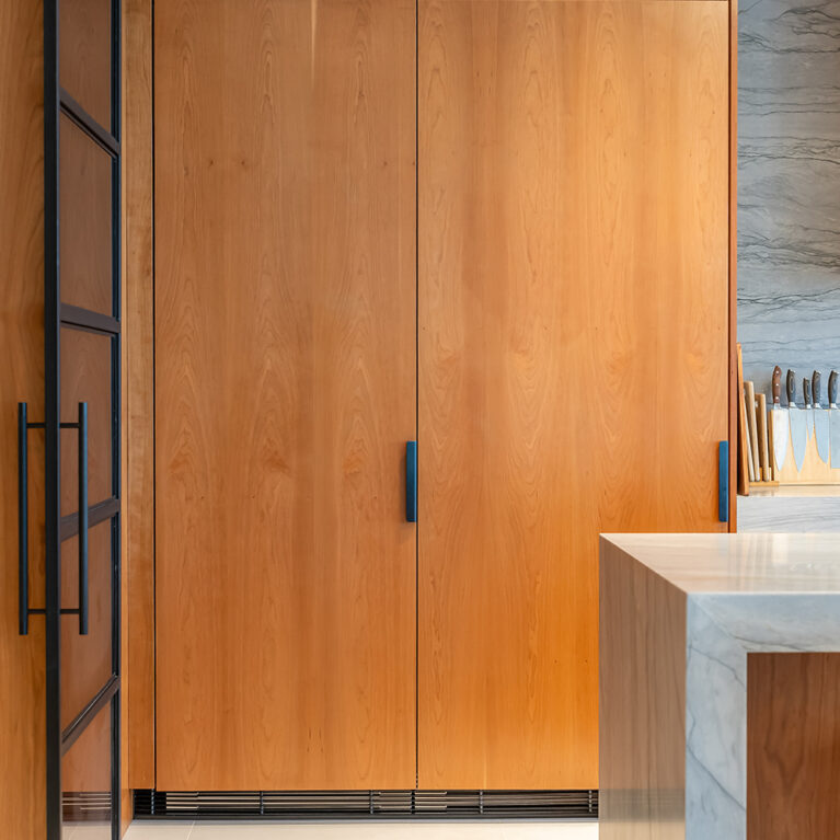 The light-brown wooden cabinets housing an integrated fridge/freezer, showcasing modern design and elegant materials.