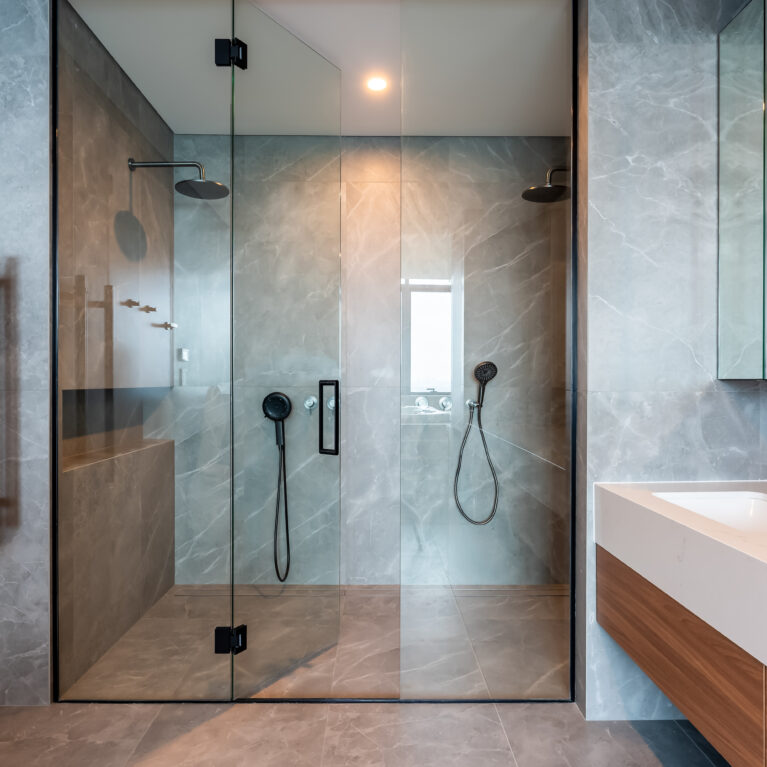 The master ensuite’s double shower provides a luxurious experience, with dual rain showerheads, gray stone tiles, and glass doors. This spacious design combines functionality with a high-end aesthetic for ultimate comfort.