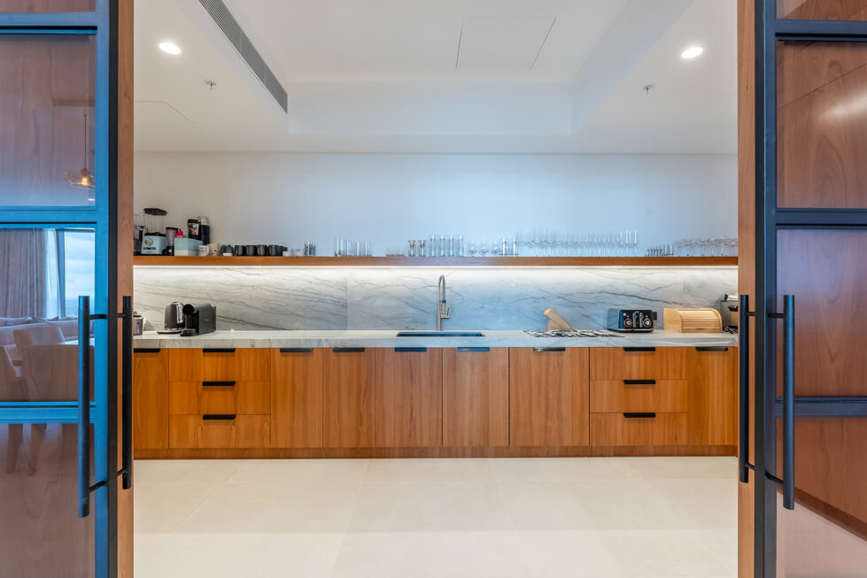 The butler’s pantry offers a practical yet stylish extension of the kitchen, with extensive storage, marble countertops, and warm wood finishes. 