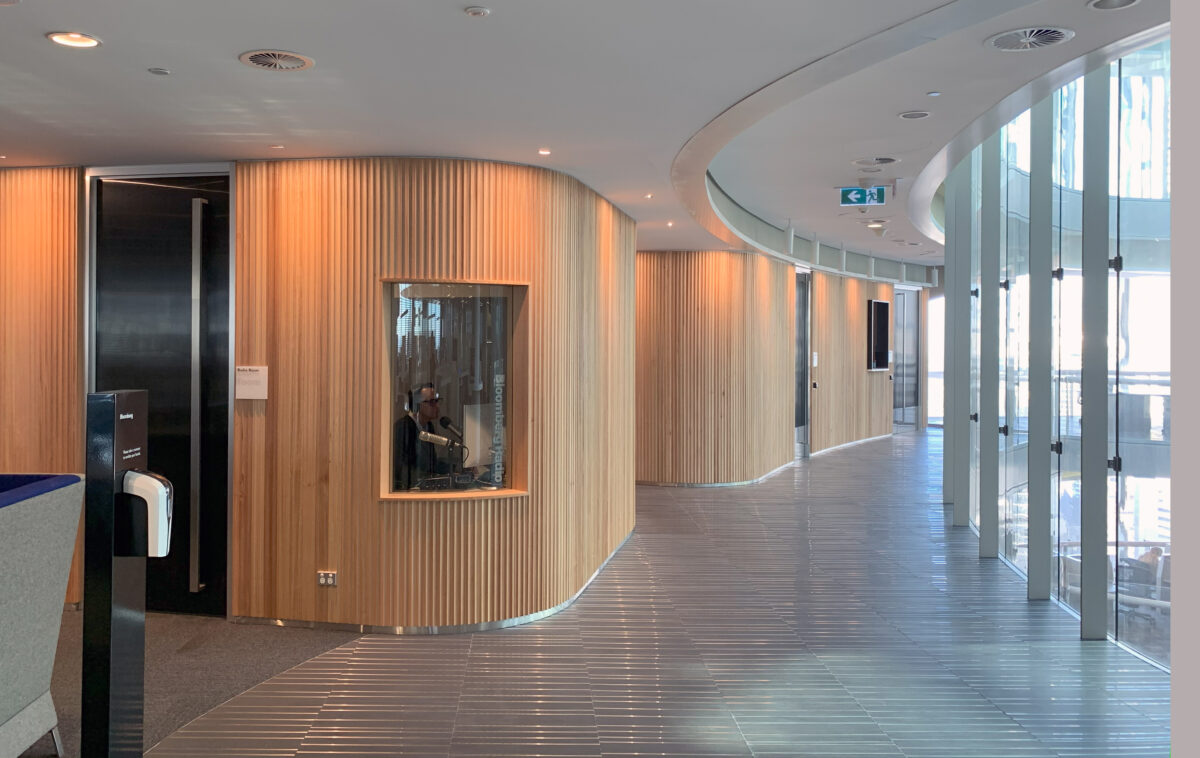 A flowing timber wall wraps around the floorplate, discreetly enclosing a sound-proof radio studio and make-up room while maintaining the office’s open, light-filled aesthetic.