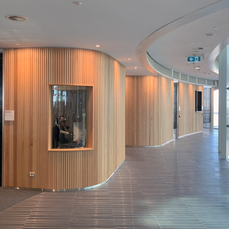 A flowing timber wall wraps around the floorplate, discreetly enclosing a sound-proof radio studio and make-up room while maintaining the office’s open, light-filled aesthetic.